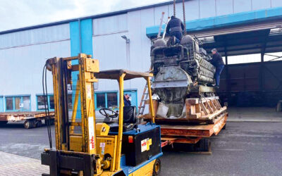 Ein Gabelstapler manövriert einen riesigen Schiffsmotor in eine Halle