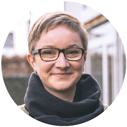 Porträt von Johanna Zschornak, die Aufnahme ist draußen entstanden, im Hintergrund ist eine Fensterfront zu erkennen