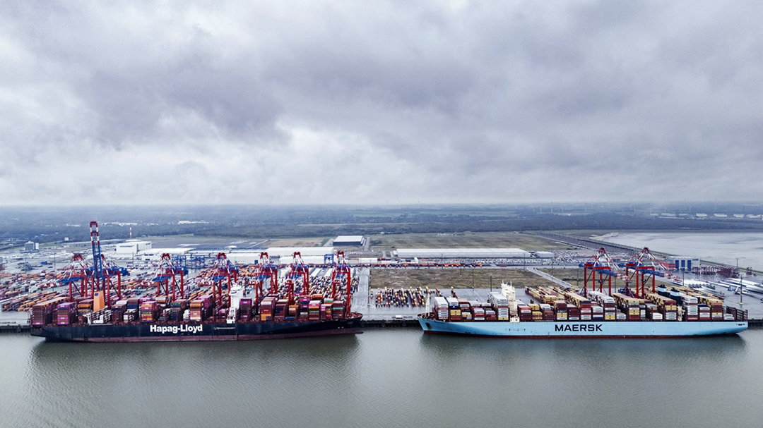 Two container ships are moored side by side in the harbour