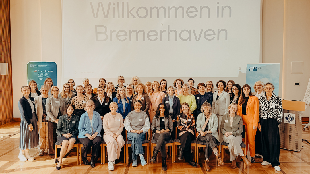 A group photo of the approximately 40 attendees at the Business Dialogue for Female Entrepreneurs in Northern Germany. In the background, a screen displays the words ‘Welcome to Bremerhaven’; the room is bright and spacious.