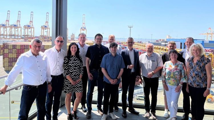 Dreizehn Teilnehmende des Forums in einem Gruppenbild. Im hintergrund sind Hafen und Kräne sichtbar.