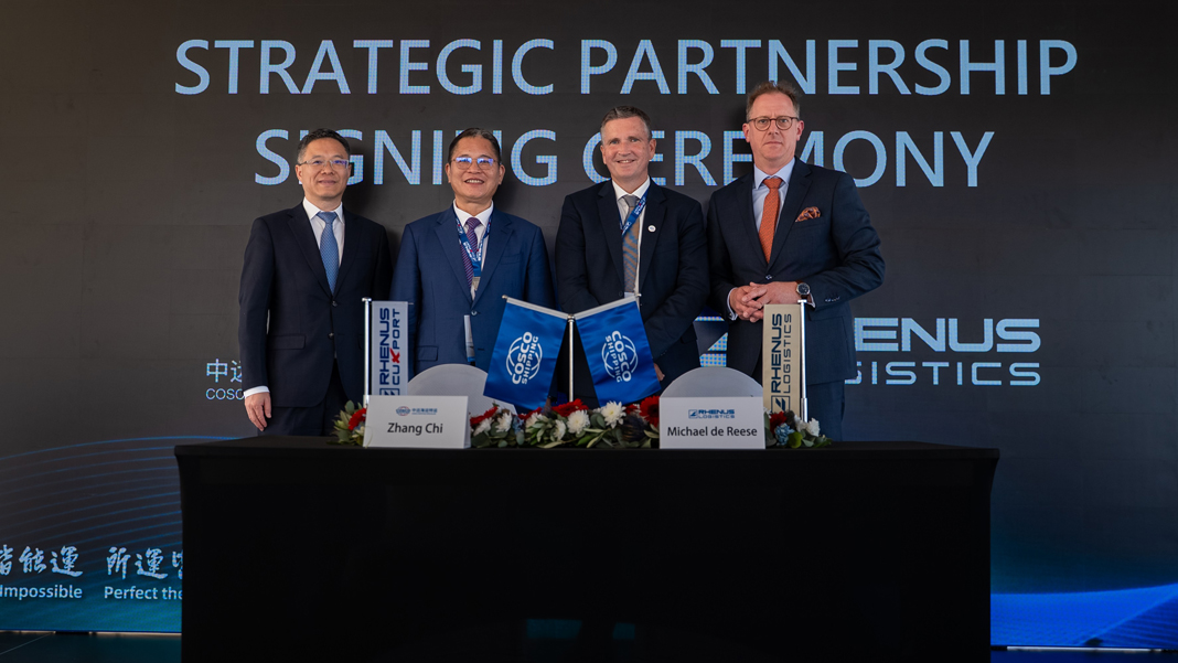 Feierliche Unterzeichnung Zwei Vertreter von Cosco und zwei Vertreter von Rhenus ´stehen an einem geschmückten tisch und blicken in die Kamera. Auf einer Wand dahinter steht in großen Buchstaben STRATEGIC PARTNERSHIP SIGNING CEREMONY