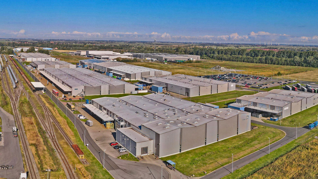 Luftaufnahme des Industriepark Emden, mehrere industrielle Hallen neben denen Bahngleise verlaufen, im Hintergrund Grünflächen/Natur