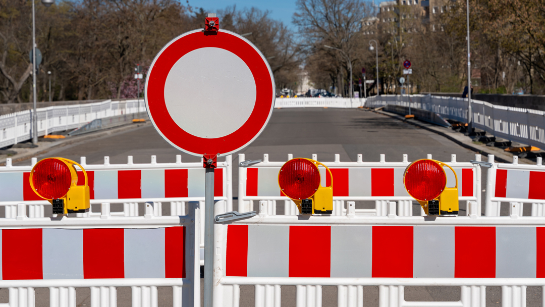Construction site barrier with traffic sign no entry rot weiße Absperrungen mit einem Durchfahrt-Verboten-Schild, die eine Straße absperren.